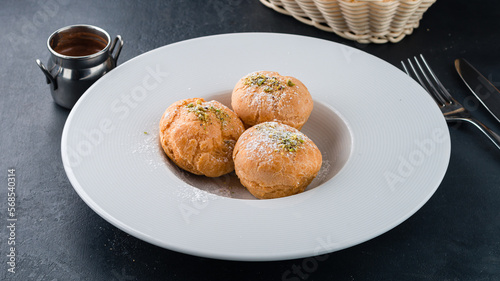 French profiteroles stuffed with whipping cream in plate. photo