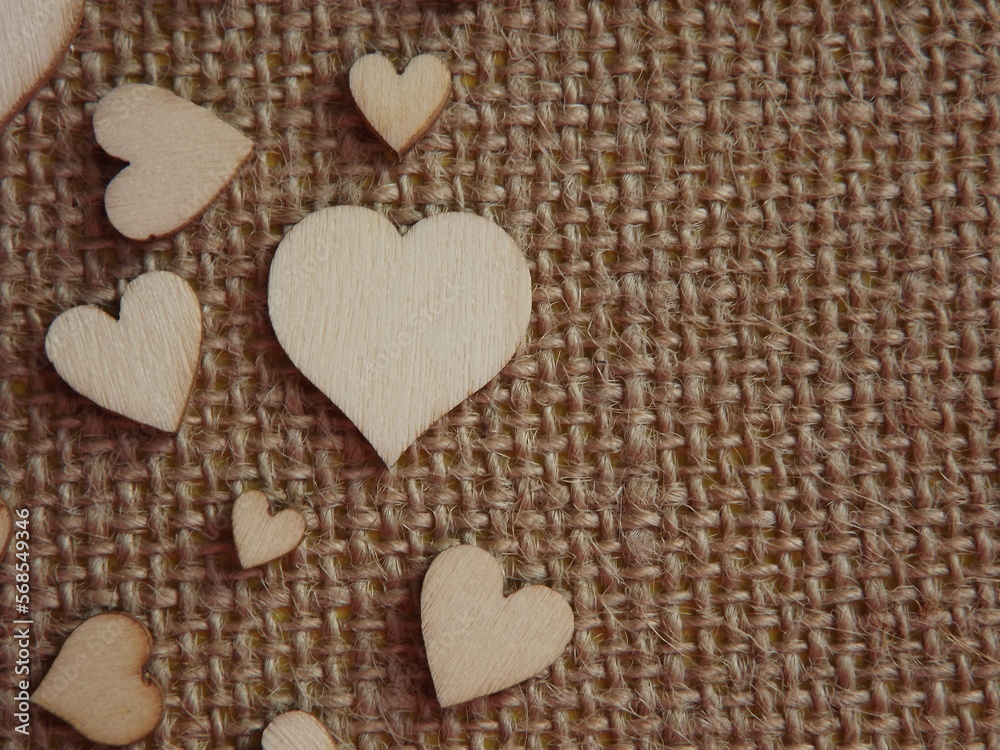 Obraz premium wooden hearts of different sizes on jute fabric as a Valentine's day greeting card. High quality photo