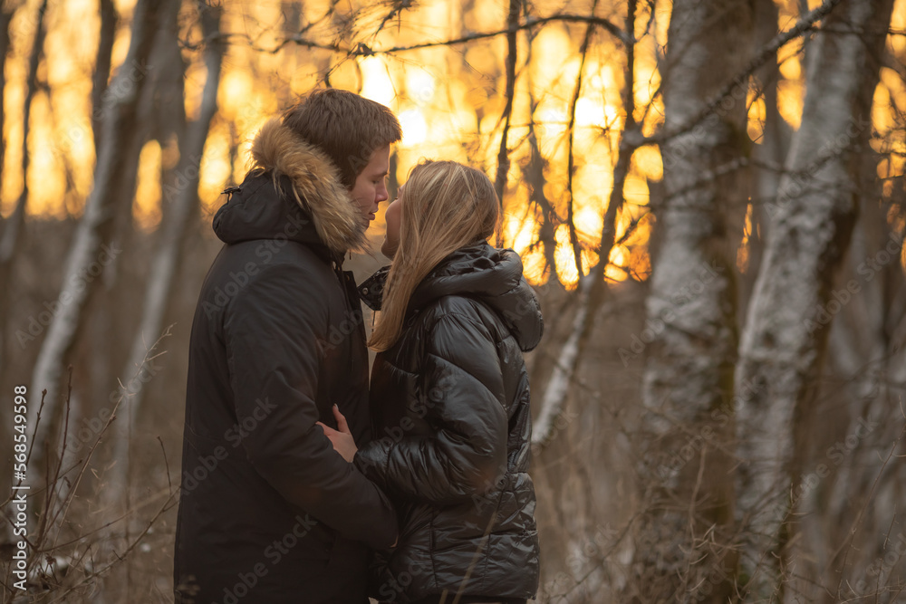 Valentine's day date. Young stylish loving couple walking in winter park. Man and woman hugging enjoying sunset landscape outdoors Valentine's day date. Young stylish loving couple walking in winter park. Man and woman hugging enjoying sunset landscape outdoors