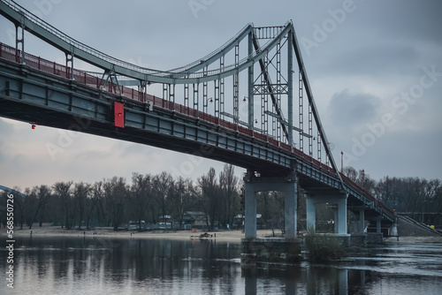 Pedestrian bridge with a bike path across the Dnieper River in the center of Kyiv, on a cloudy spring day