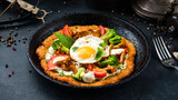 Fried big potato pancake with chanterelle mushrooms, tomatoes, broccoli, egg, onion, herbs and sour cream in a frying pan.
