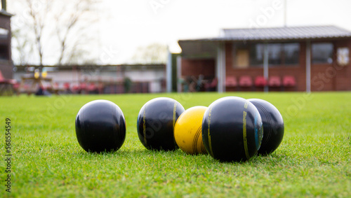 Crown green bowling balls gathered round the yellow Jack during bowling competition outdoors  a popular sport in the UK