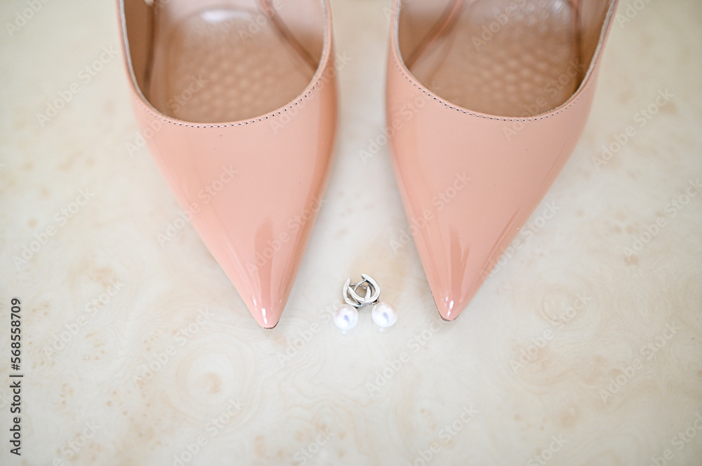 Fototapeta premium The bride earrings in white gold with diamonds lie on table next to shoes.