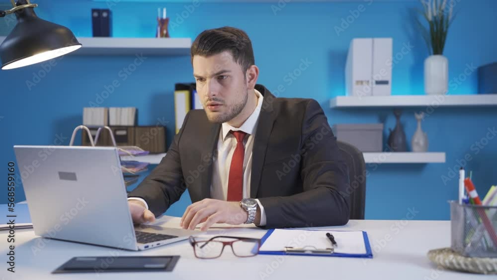 Young business man working at his desk in office reading bad and boring mail or news on screen while working on laptop and gets frustrated. Young business man working at his desk in office reading bad and boring mail or news on screen while working on laptop and gets frustrated.