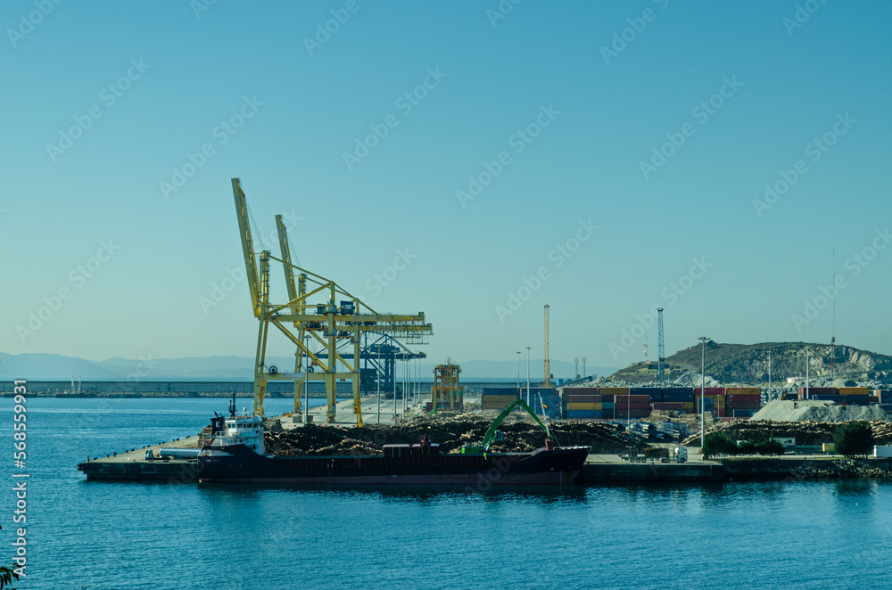 Cranes of the port of Ferrol and a ship loading wood