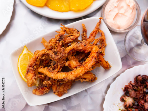 Popular Spanish tapa Rejos - fried spicy tentacles of squid served with lemon slice and sauces