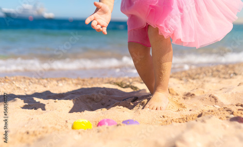 Kid girl on Easter egg hunt on the sandy beach. Happy Easter holidays concept  © BooFamily