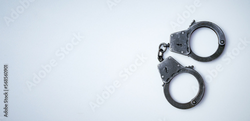 Closed police handcuffs on a white rectangular background. Banner for criminal news. Arrest. photo