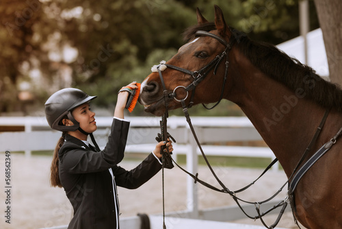 Girl taking care of her horse before horse riding. Equestrian sport. © JJ Studio