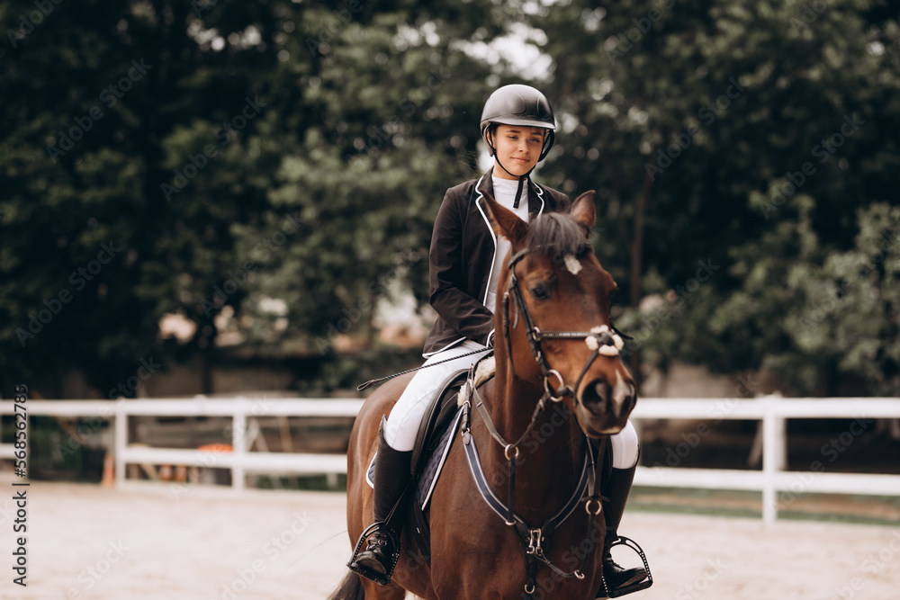 Young woman in special uniform and helmet riding horse. Equestrian sport - dressage.