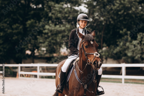 Young woman in special uniform and helmet riding horse. Equestrian sport - dressage. © JJ Studio