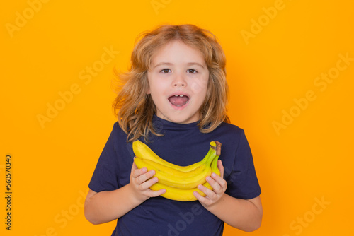 Banana. Child hold banana in studio. Studio portrait of cute kid boy with bananas isolated on yellow background, copy space.