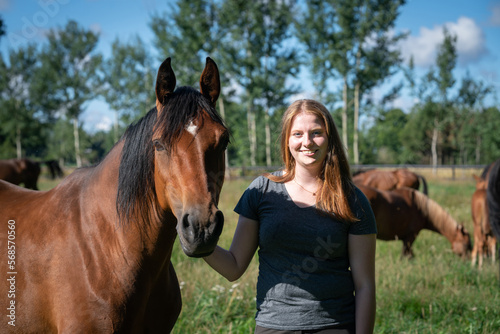 Junge Frau freut sich, das ihr Pferd auf einer grünen Wiese steht. © Countrypixel