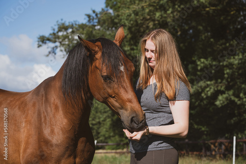 Ein Pferd frisst einer jungen Frau, Leckerlies aus der Hand. © Countrypixel