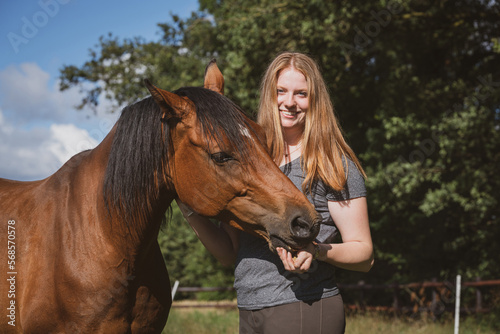 Ein Pferd frisst einer jungen Frau, Leckerlies aus der Hand. © Countrypixel