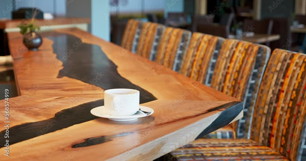 Coffee espresso cup sitting on an empty bar top in a nice restaurant. Custom made live edge bar top with black epoxy. Slow panning shot of an empty bar at a fancy restaurant. 