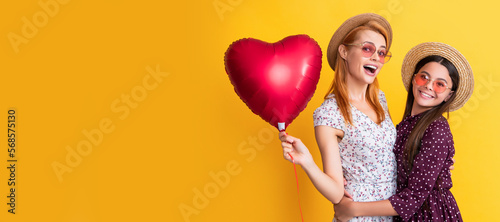 Mother and daughter kid banner, copy space, isolated background. mom and daughter smile hold love heart balloon on yellow background.