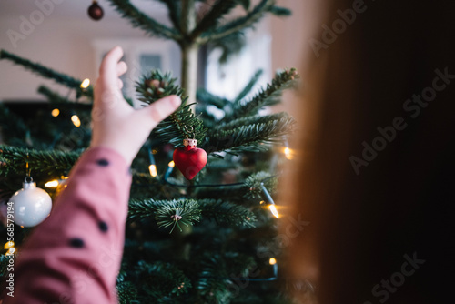 Kind schmückt Weihnachtsbaum (ID: 568579194)