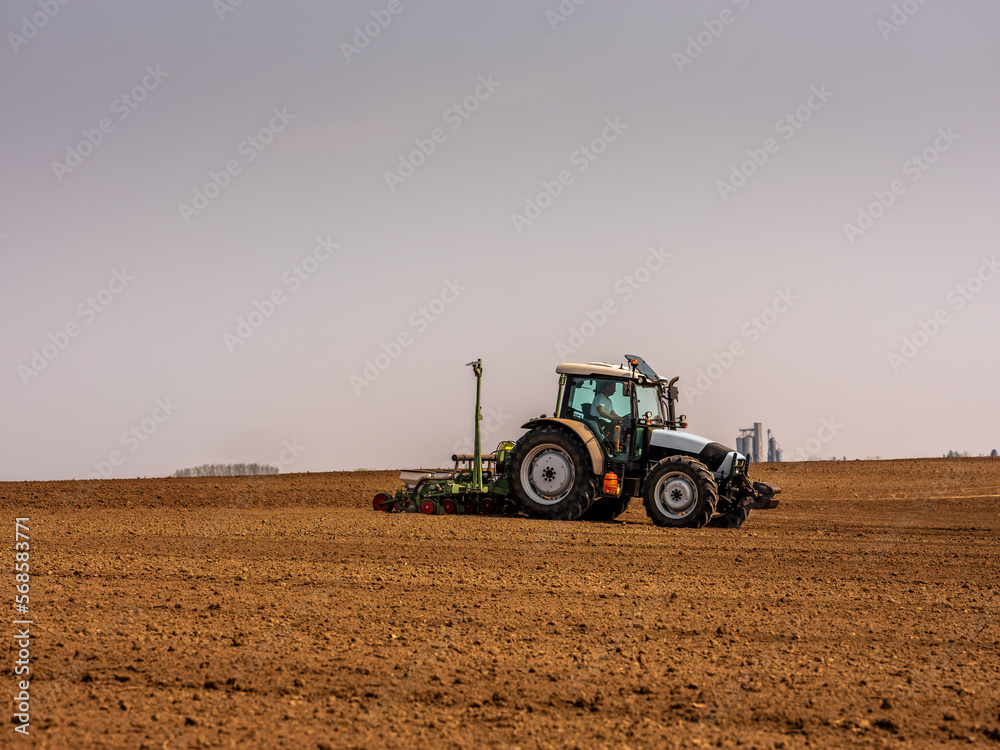 Fototapeta premium Farmer planting soybean seeds in a field with a tracto