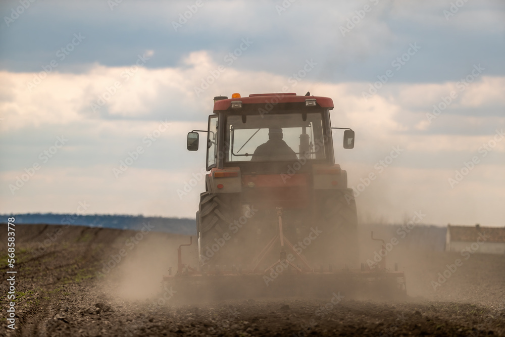 Fototapeta premium Springtime seeding preparations, tractor at work on the fertile fields