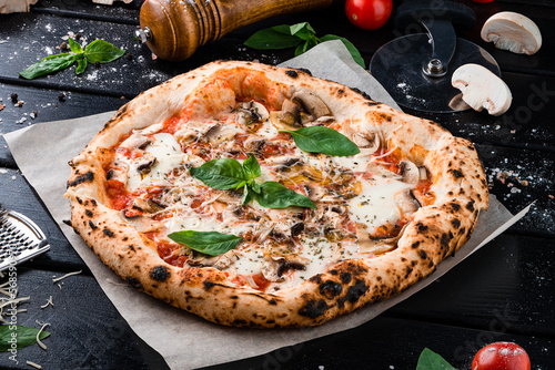 Fresh Neapolitan pizza with cheese parmesan, champignon mushrooms, tomato sauce, spinach on thick dough with spices from oven.