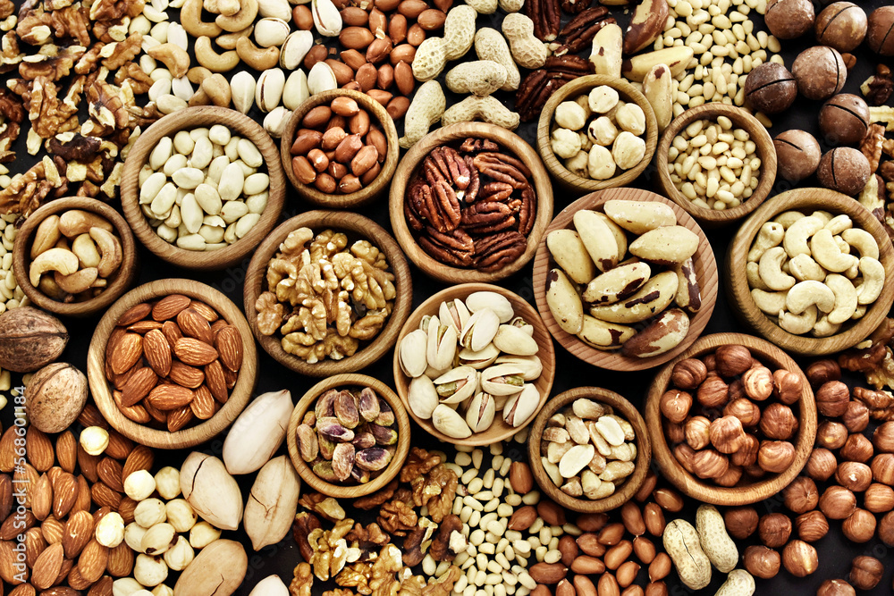 Colorful mix of various nuts: peanut and cashew, hazelnut and almond, pine nuts and walnut; healthy diet snack; vegan food background	