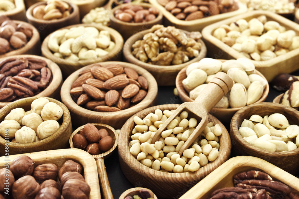 Colorful mix of various nuts: peanut and cashew, hazelnut and almond, pine nuts and walnut; healthy diet snack; vegan food background, selective focus, shallow DOF