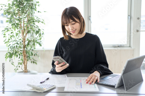 Fotografía スマートフォンで確定申告をするアジア人女性