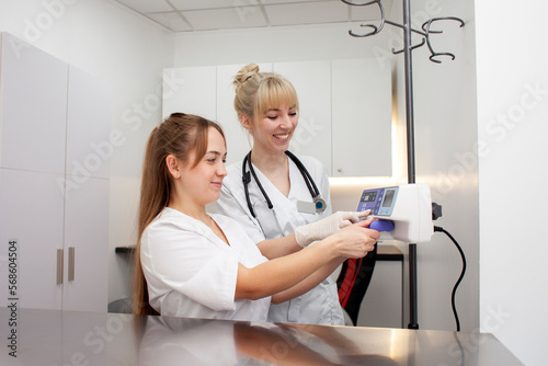 two female nurses in uniform connect an infusion pump in a hospital, young female doctors in medical gowns photo