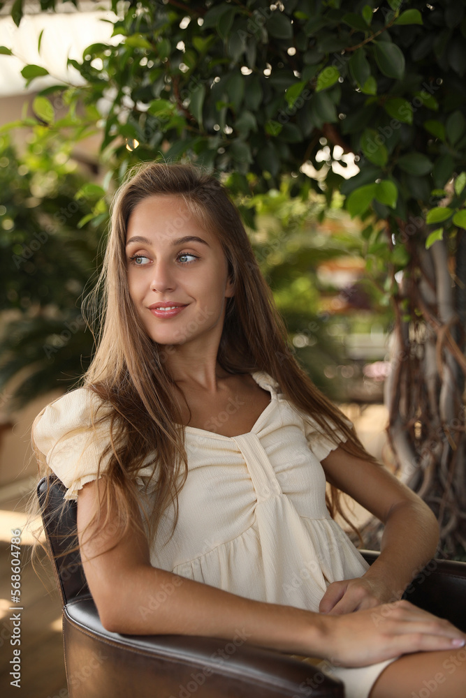 Beautiful young woman sitting on indoor terrace in cafe Beautiful young woman sitting on indoor terrace in cafe