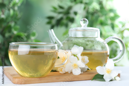 Tasty tea and fresh jasmine flowers on white wooden table