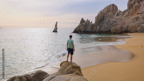 Man standing on rock at Lover's Beach in Cabo San Lucas, Mexico photo