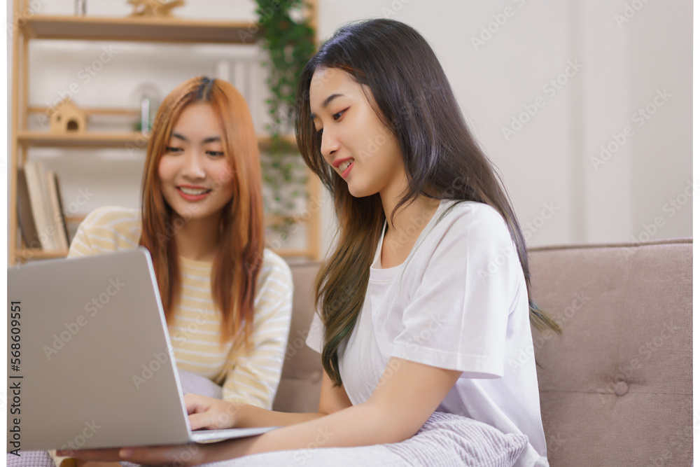 Activity at home concept, LGBT lesbian couple read and typing data on laptop while working together Activity at home concept, LGBT lesbian couple read and typing data on laptop while working together