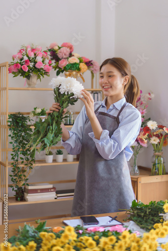 Floristry concept, Woman florist holding white chrysanthemum with smiling happiness in flower shop