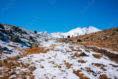 A snowy path leads up to the peak in the Greater Caucasus mountains in Georgia. A blue sky above for copy space.