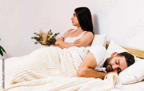 Overhead of young couple in the bed. Attractive woman is angy with her sleeping boyfriend. photo