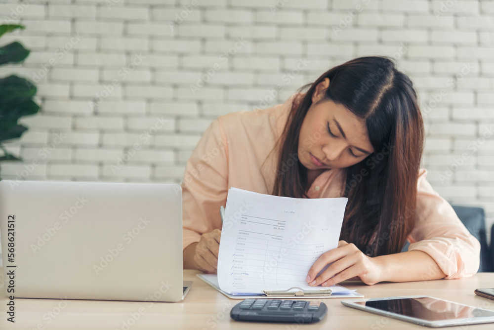 Asian Female freelance using laptop at home office desk. Woman reading financial graph chart Planning analyzing marketing data. Asian female people working office firm with business stuff, coffee cup Asian Female freelance using laptop at home office desk. Woman reading financial graph chart Planning analyzing marketing data. Asian female people working office firm with business stuff, coffee cup