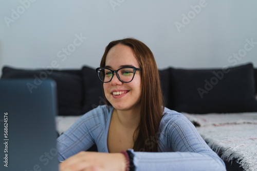 A young girl is studying or doing business from home on her laptop