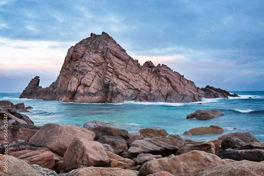 Cloudy sunrise Sugar Loaf Rock. A large granite boulder in the Indian Ocean off the coast of south west of Western Australia