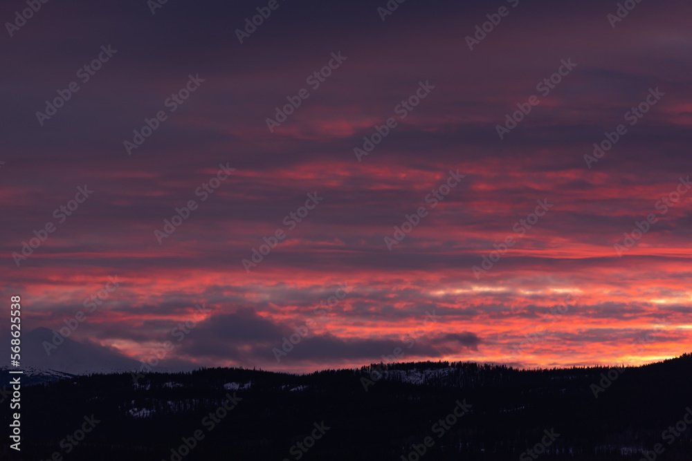 Incredible sunset views in winter season from northern Canada with bright pink clouds, mountains and snow at dusk.