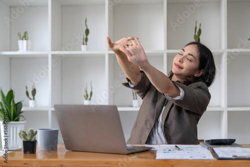 Photos Business women stretch oneself or lazily for relaxation on her desk while doing