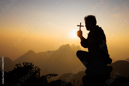 Silhouette of christian man hand praying, man holding a crucifix praying, spirituality and religion, woman praying to god. Christianity concept.
