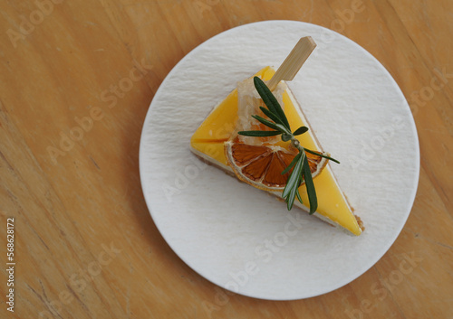 top view fresh honeyslice, dry orange slice, green leaf on yuzu cheese pie on white ceramic plate on wooden table background, food, dessert, copy space