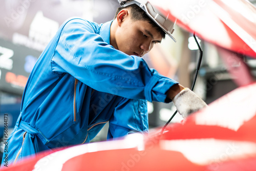 Asian automotive mechanic man checking car damage broken part  condition, diagnostic and fixing vehicle at auto repair garage shop , motor technician maintenance after service concept © winnievinzence