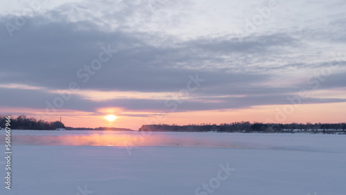 Winter sunset on the big river, hummocks in the rays of the sun. © nikolay_alekhin