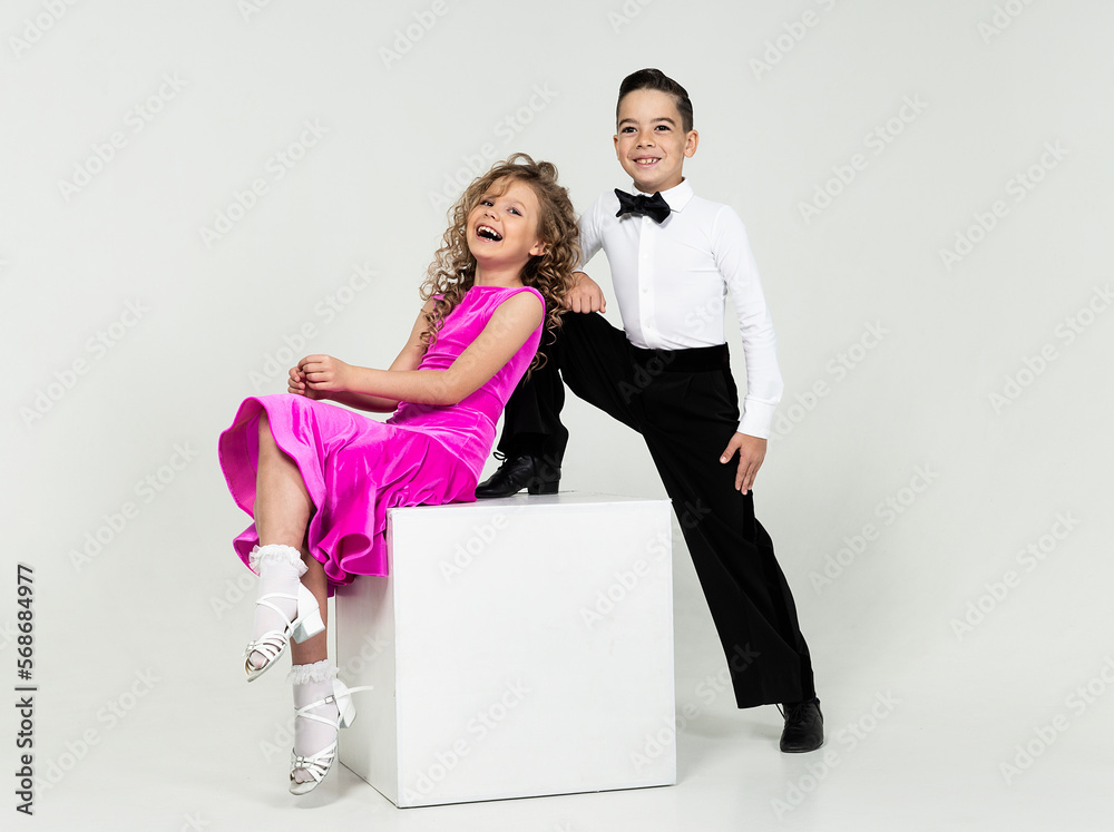 curly-haired girl and a boy engaged in ballroom dancing sit posing at a ...