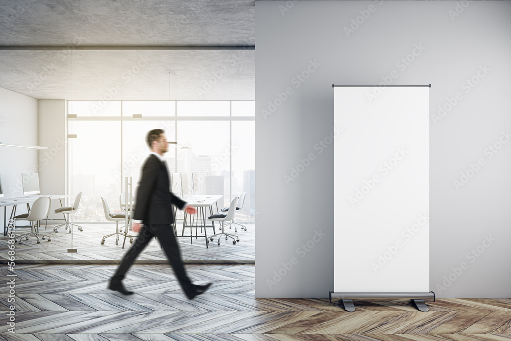 Φωτογραφία Businessman walking in modern glass office interior with empty mock up banner on wall, wooden flooring, furniture, window with city view and other objects