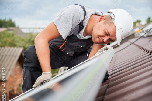 Foto Man technician mounting photovoltaic solar moduls on roof of house