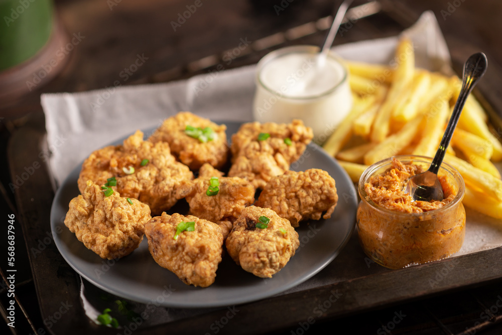 Pieces of flour-fried cauliflower with vegan sauces on a plate on a dark background. Cauliflower wings food. Pieces of flour-fried cauliflower with vegan sauces on a plate on a dark background. Cauliflower wings food.