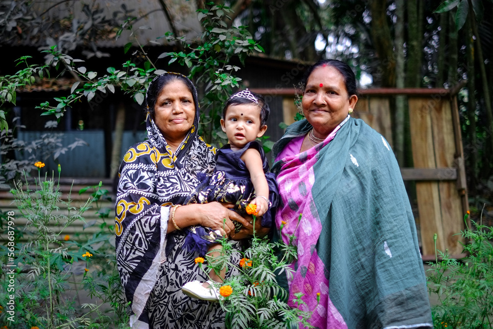 South asian grandmothers with their common granddaughter in outdoor environment within a marigold garden South asian grandmothers with their common granddaughter in outdoor environment within a marigold garden